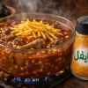 ادویه خورشت قیمه اسپایفل در نمکدان شیشهای کنار خورشت قیمه در حال پخت